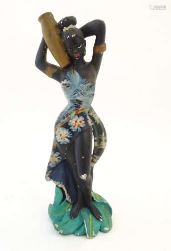 A 20thC model of an African lady in an floral dress carrying...