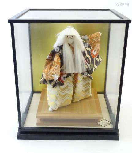 A 20thC Japanese kabuki doll in traditional dress. Within a ...