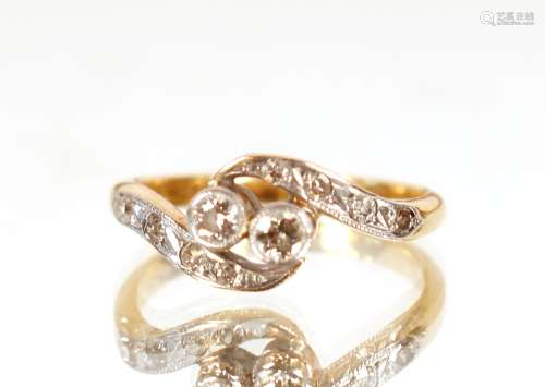 An 18ct gold and platinum cross over ring, set with diamonds...