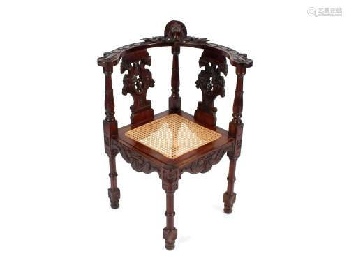 A carved mahogany corner chair, with profuse mask and foliat...