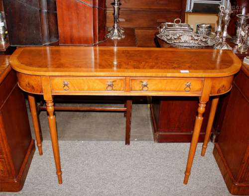 A walnut bow fronted two drawer hall table, raised on turned...
