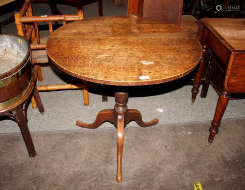 A 19th Century oak circular snap top occasional table, raise...