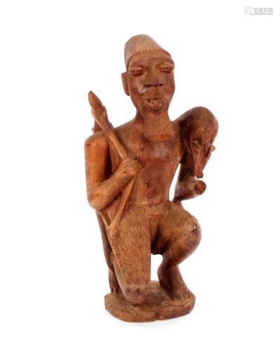 An unusual ethnic carving of crouching bearded figure, carry...