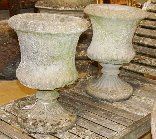 A pair of reconstituted stone campana-shaped urns on stands,...