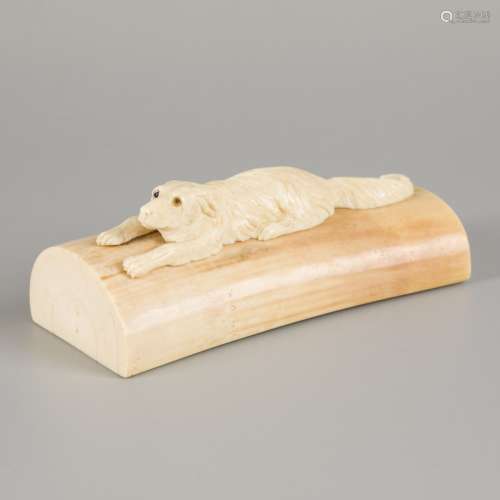 An ivory presse-papier with carved reclining dog, 1st half 2...