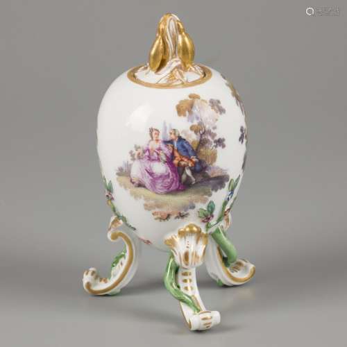 A porcelain egg on legs and a leaf-shaped knob, decorated wi...