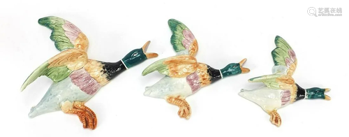 Three porcelain flying ducks wall plaques, the largest