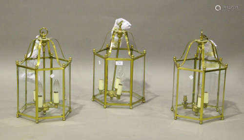 A set of three modern brass framed ceiling lanterns with gla...
