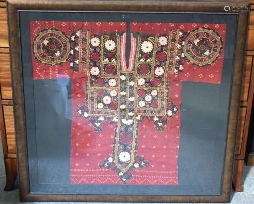 A framed Chinese fabric in the shape of a gown. 83 x 87 cm.