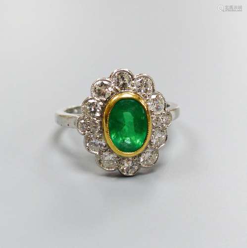 A modern platinum, emerald and diamond set oval cluster ring...