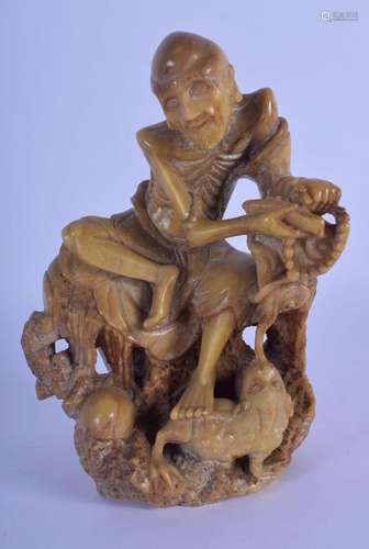 A 19TH CENTURY CHINESE CARVED SOAPSTONE FIGURE OF AN EMACIAT...