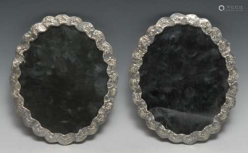 Une paire de miroirs turcs ovales en argent, ciselés de fleu...