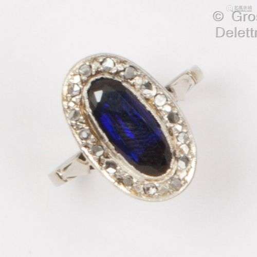 Bague ovale en or gris, ornée d’une pierre bleue dans un ent...