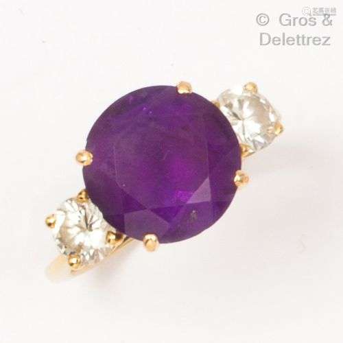 Bague en or jaune, ornée d’une pierre violette épaulée de de...