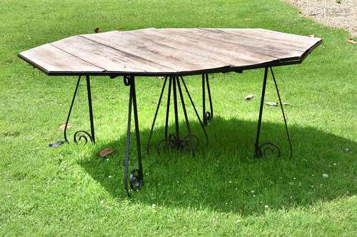 A large wrought iron and wood garden table