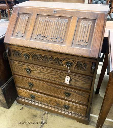 A reproduction oak linenfold carved bureau, W.75cm D.48cm H....