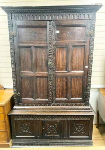 A carved oak cupboard, enclosed by panelled doors, bearing m...