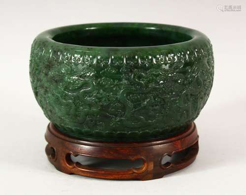 A CHINESE GREEN HARDSTONE BOWL AND STAND, carved with a band...