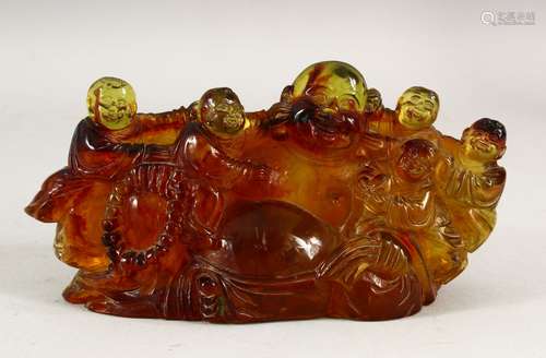 AN AMBER STYLE GROUP OF LAUGHING BUDDHA, surrounded by child...