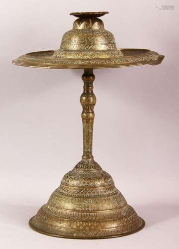 AN ISLAMIC BRASS CANDLESTICK, engraved with bands of calligr...