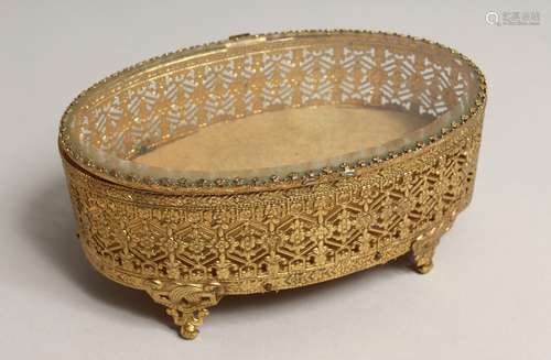 A FRENCH OVAL GILDED METAL JEWEL BOX AND GLASS COVER 7ins