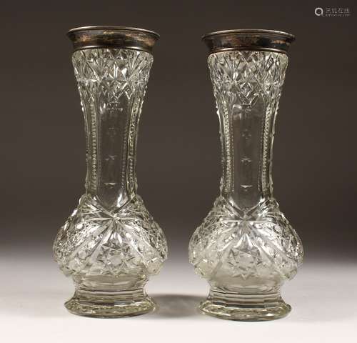 A PAIR OF CUT GLASS VASES with silver tops. 12ins high.