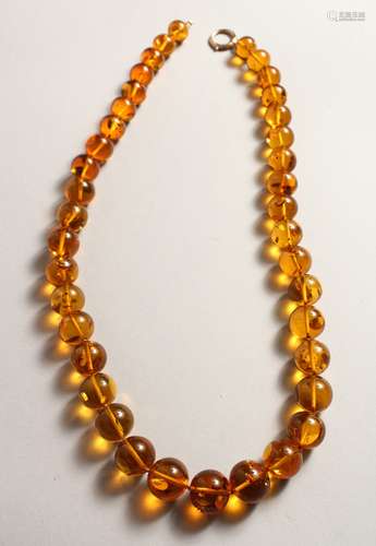 A STRING OF THIRTY NINE GRADUATED AMBER BEADS with gold clas...