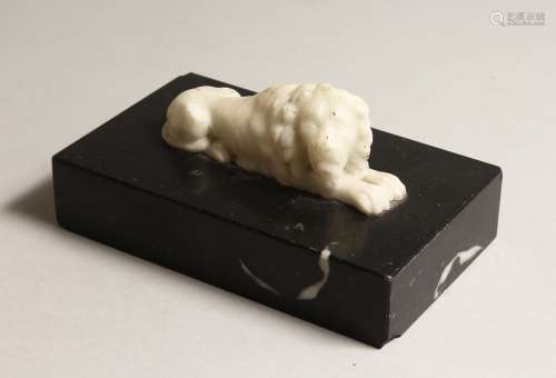 A CARVED WHITE MARBLE LION on a black base 6ins long