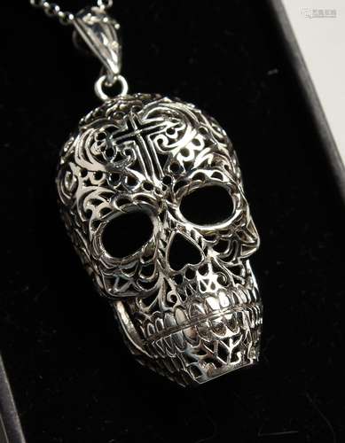 A SILVER FILIGREE SKULL on a chain.