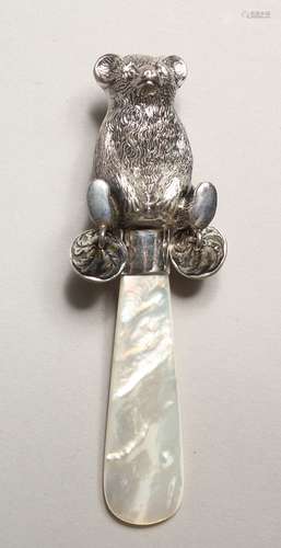 A SILVER TEDDY BEAR AND MOTHER OF PEARL RATTLE.