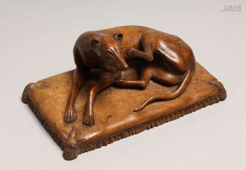 AFTER GOTT. A CARVED WOOD FIGURE OF A DOG on a cushion 6ins ...