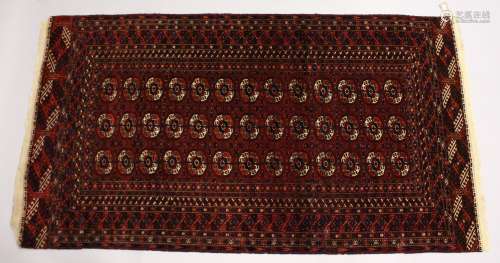 A TURKOMEN TEKKE CARPET, claret ground with three rows of th...