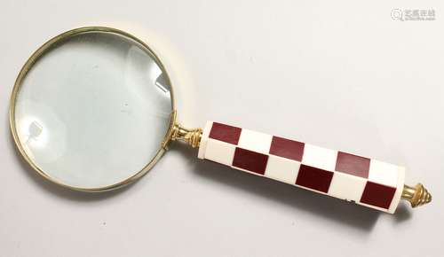 A MAGNIFYING GLASS with chequered handle.