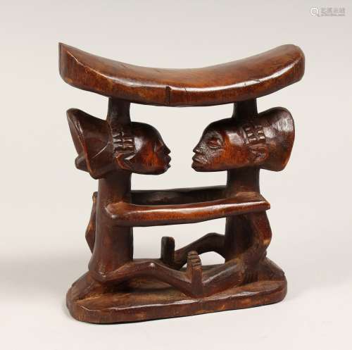 A CARVED TRIBAL HEAD REST 13ins long.
