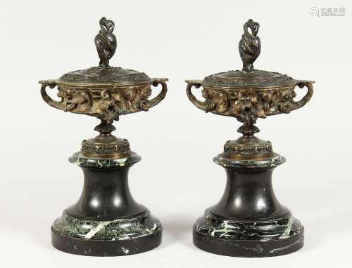 A PAIR OF BRONZE TWO HANDLED URNS AND COVERS on circular mar...