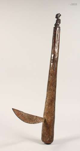 A TRIBAL WOODEN AXE carved with a figure. 23.5ins long