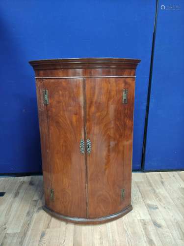 Georgian mahogany corner cupboard with two doors enclosing a...