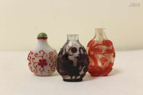 Three Chinese overlay glass snuff bottles, the first of purp...