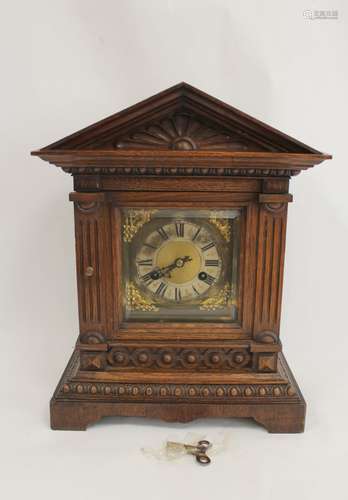 German mantel clock in carved oak case with pediment. 39cm.