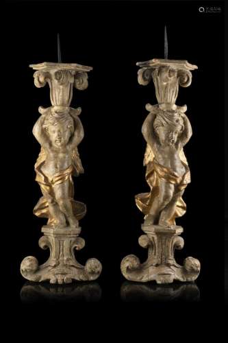A 18th century pair of carved and partially gilded candle ho...