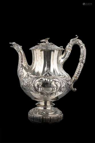 An embossed silver teapot decorated with swirls and spirals....