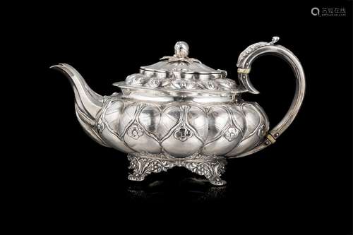 An embossed silver teapot decorated with a coat of arms. Bon...