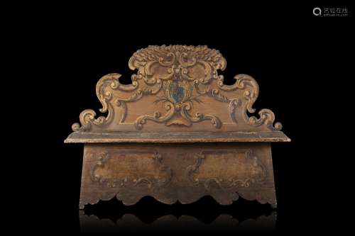 A carved and lacquered wooden settle decorated with a coat o...