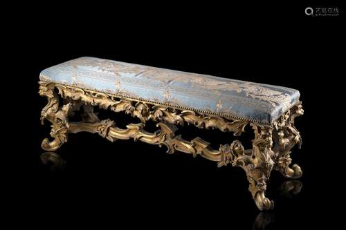 An antique sculpted and gilt wooden bench with embroided tex...