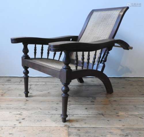 A HARDWOOD RATTAN PANELLED LOLLING CHAIR, with adjustable pe...