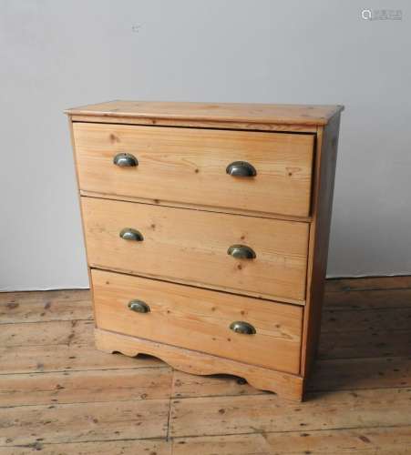 A WAXED PINE CHEST OF THREE DRAWERS, the three drawers with ...