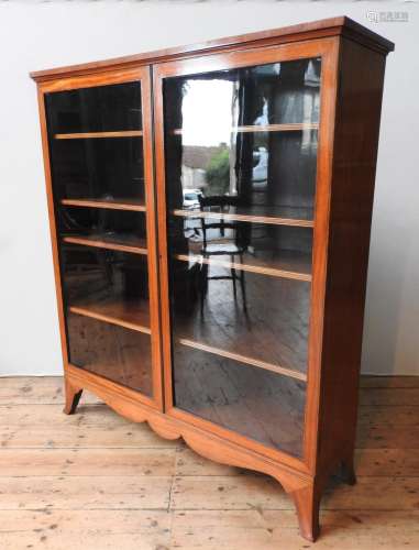 A MAHOGANY CROSS BANDED TWO DOOR GLAZED BOOKCASE ON SPLAYED ...