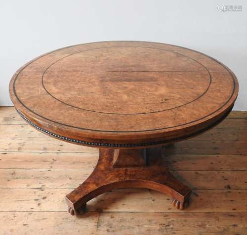 A BURR WALNUT CIRCULAR TOP DINING TABLE ON CARVED CENTRAL PE...