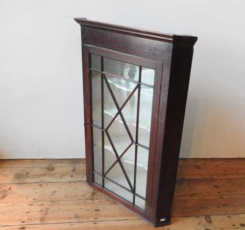 A GEORGE III GLAZED MAHOGANY WALL MOUNTED CORNER CUPBOARD, w...