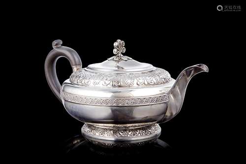 An embossed silver teapot decorated with plant motifs. Woode...